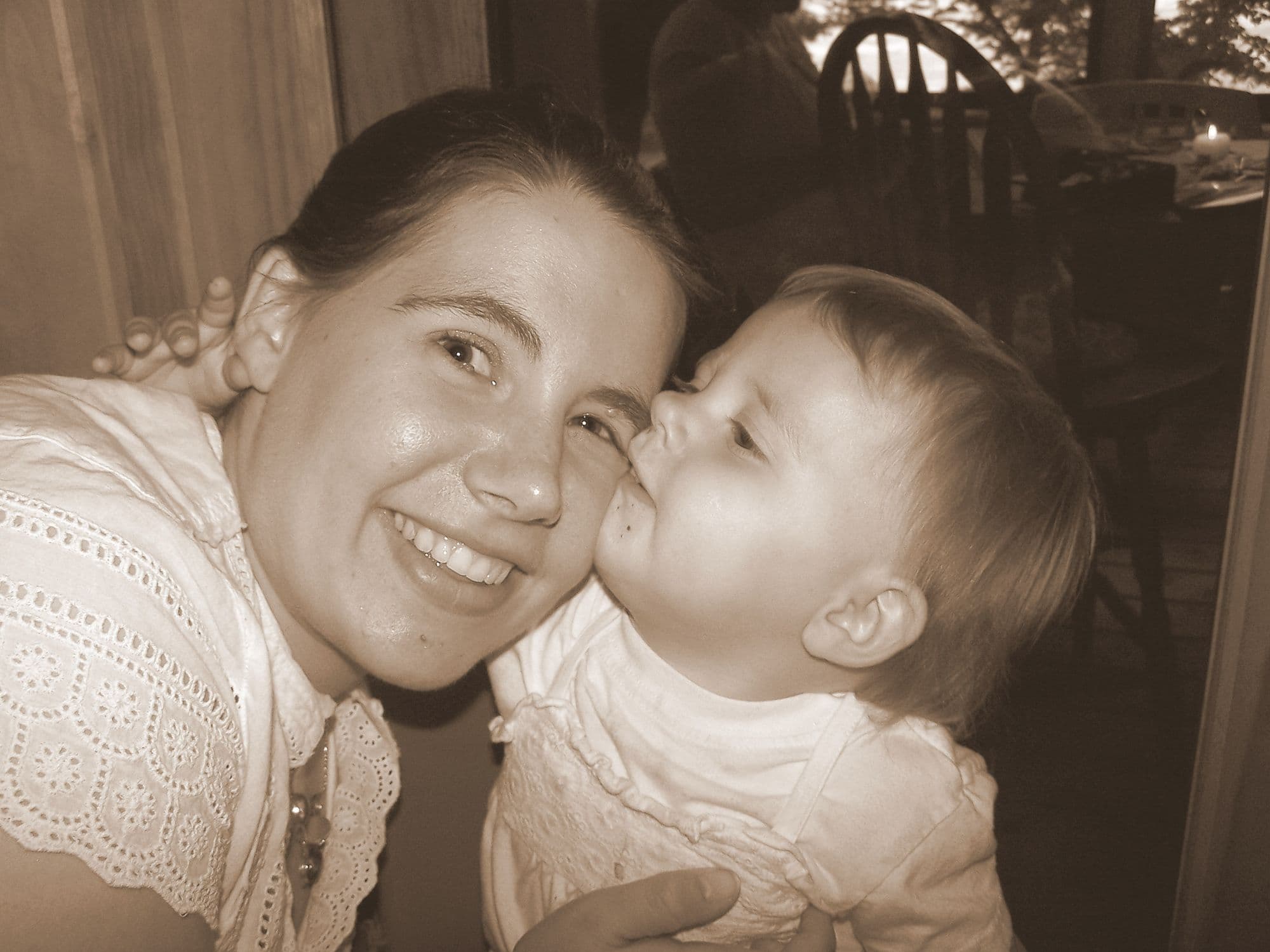 Sepia portrait of woman kissing a baby
