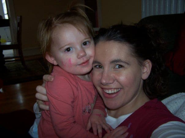 Woman holding a toddler with face paint