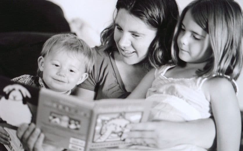Black and white photo of woman reading to children