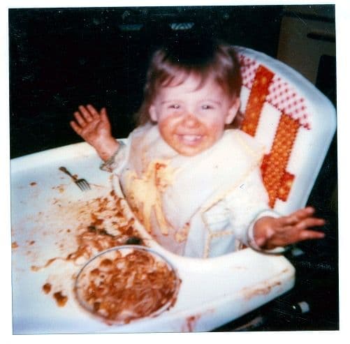 Toddler waving in a high chair
