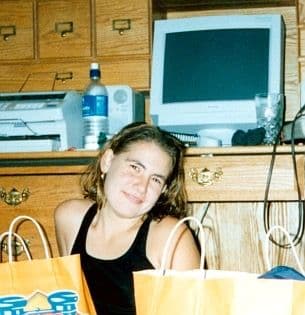 Young woman by desk with shopping bags