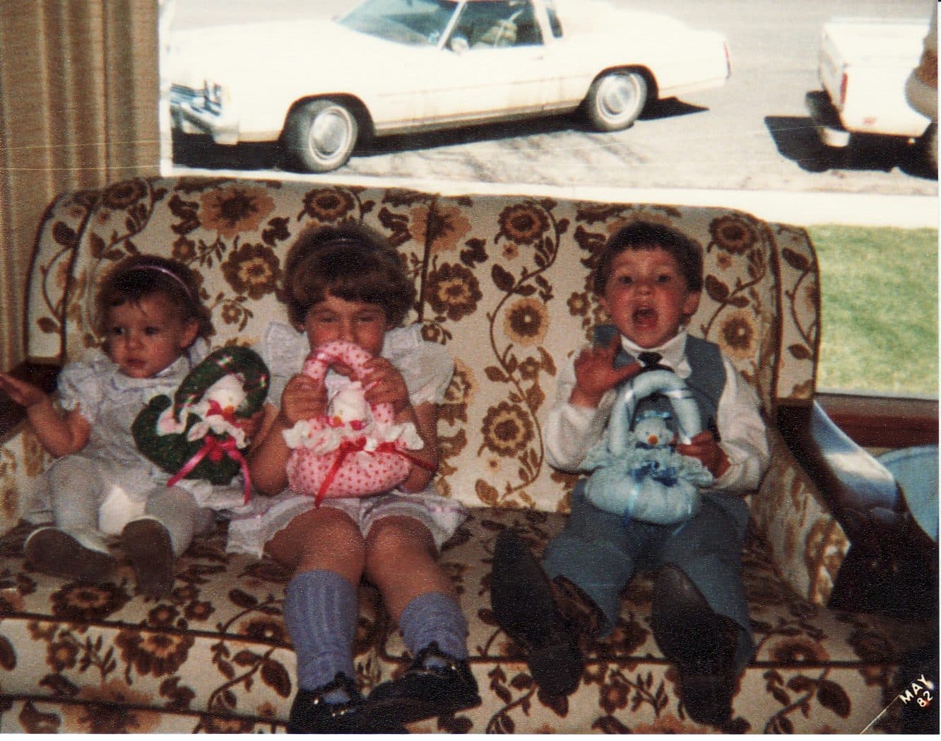 Three toddlers on a couch with toys