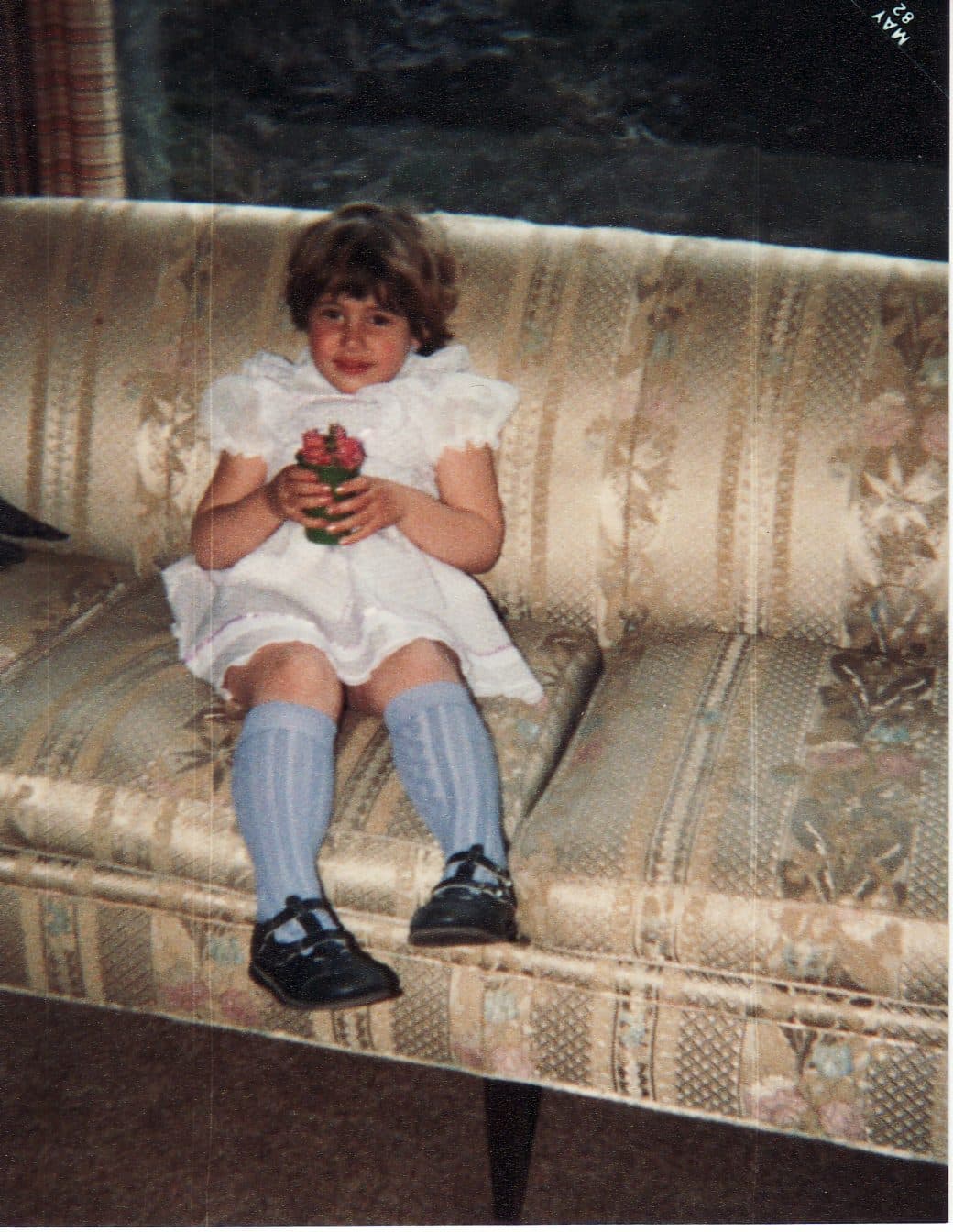 Toddler girl on a couch in a white dress