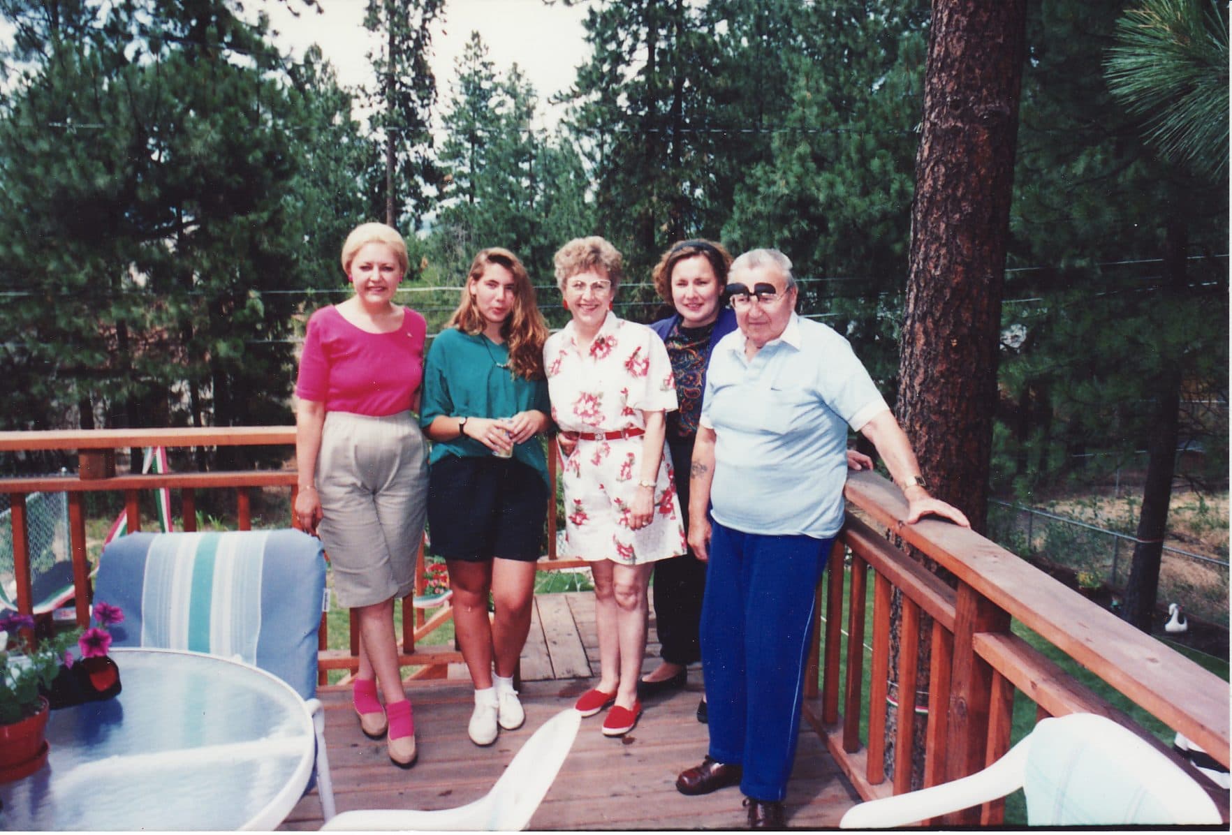 Four women standing together on a wooden deck