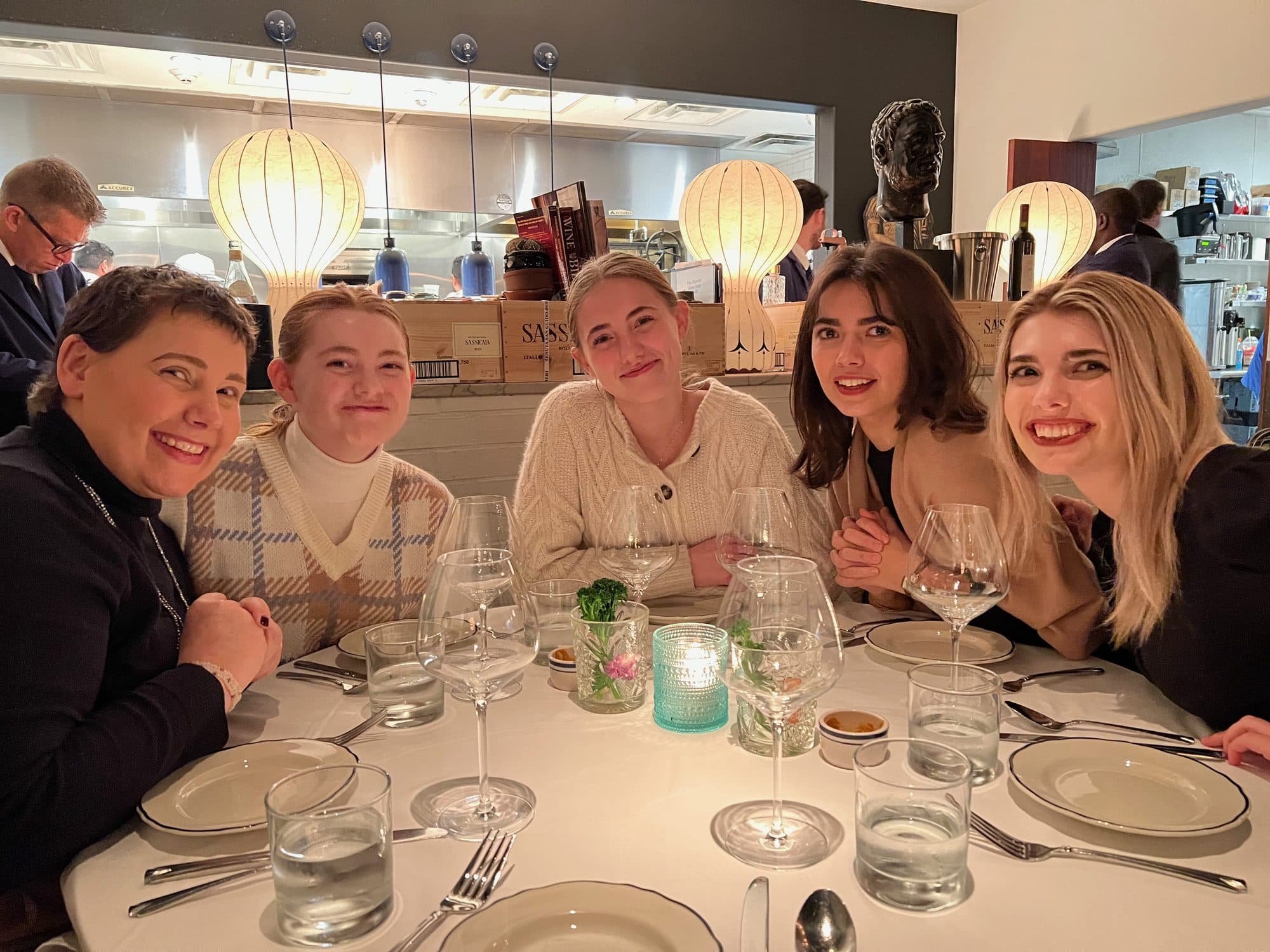 Five women posing at a restaurant dinner table