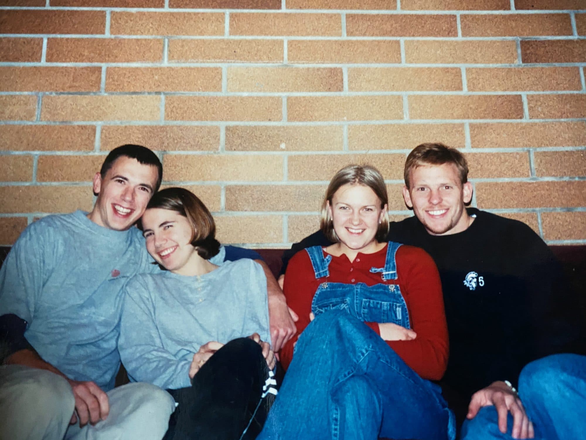 Four friends posing against a brick wall