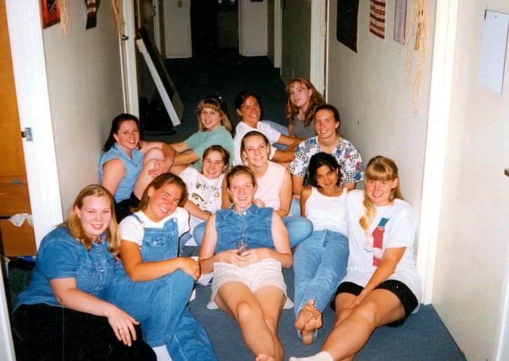 A dorm hallway full of college women sitting together on the floor