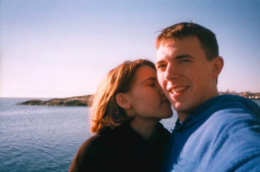 Couple cheek to cheek by the water at dusk