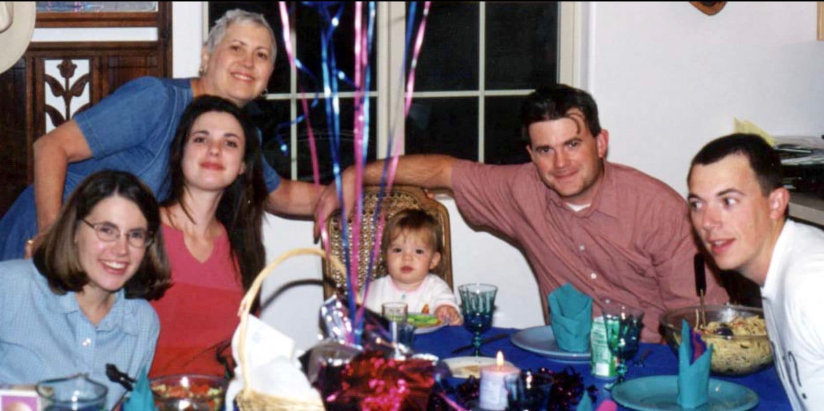 Family gathered around a birthday table with balloons