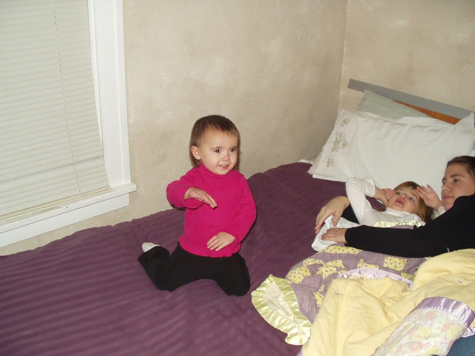 Toddler sits alone on a bed