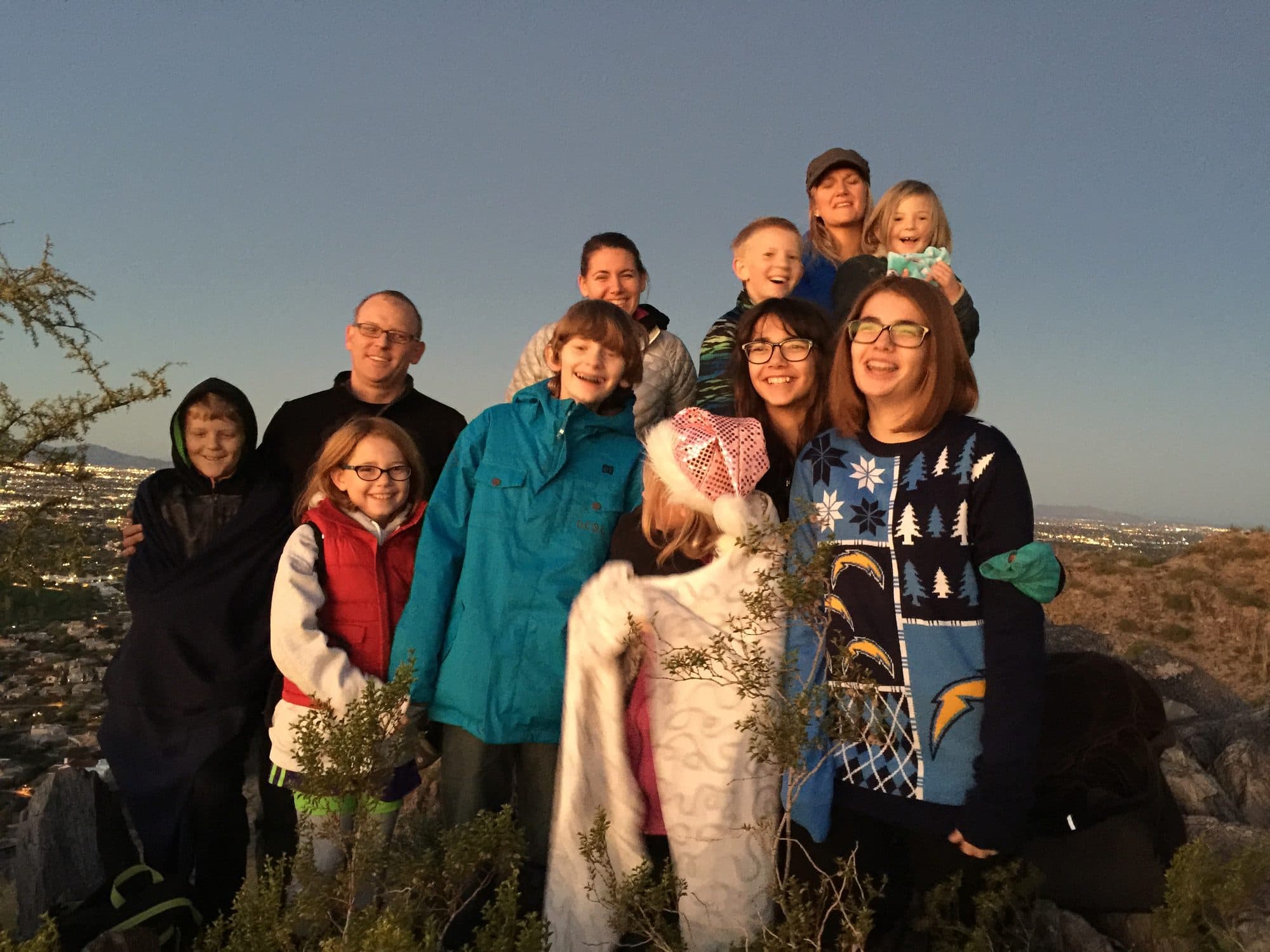 Extended family poses on a desert hillside at dusk