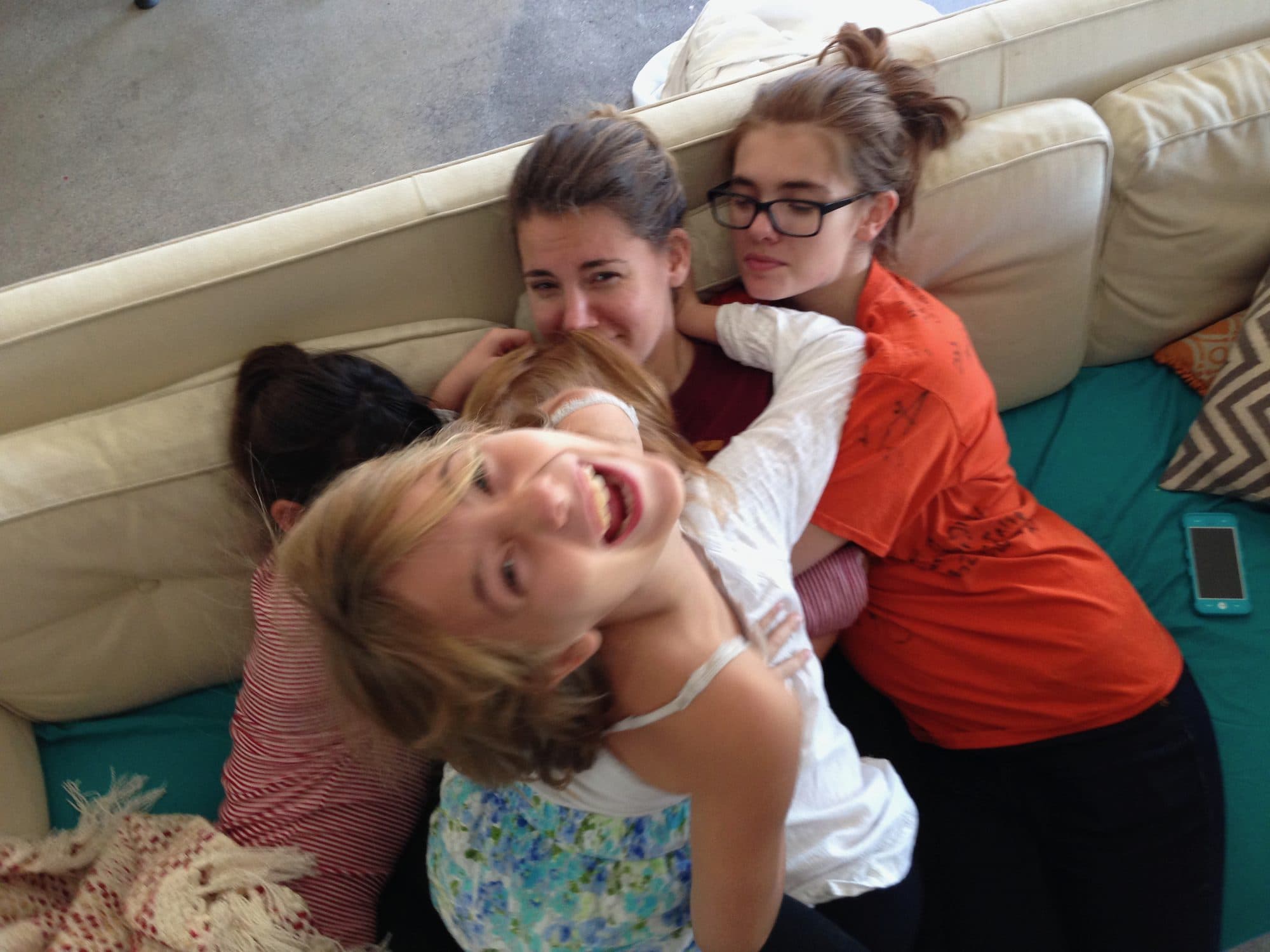 Teens pile together laughing on a couch