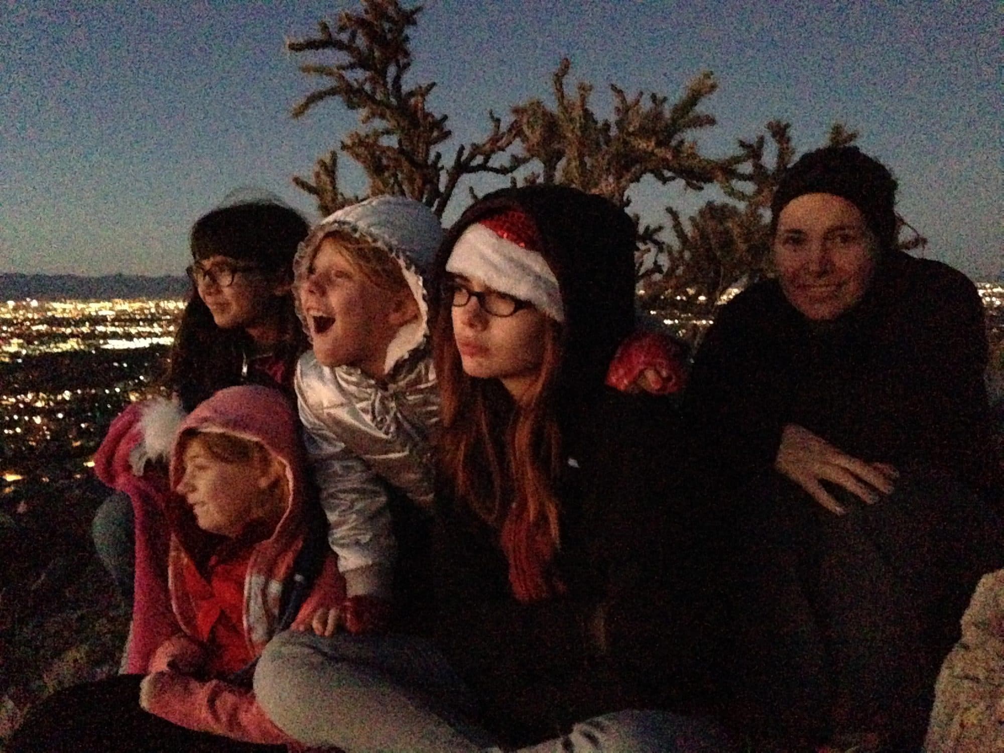 Family sits on desert rocks at dusk