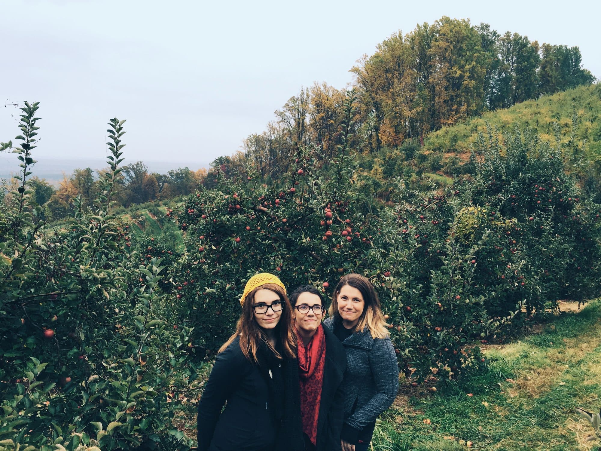 Three women pose in an apple orchard