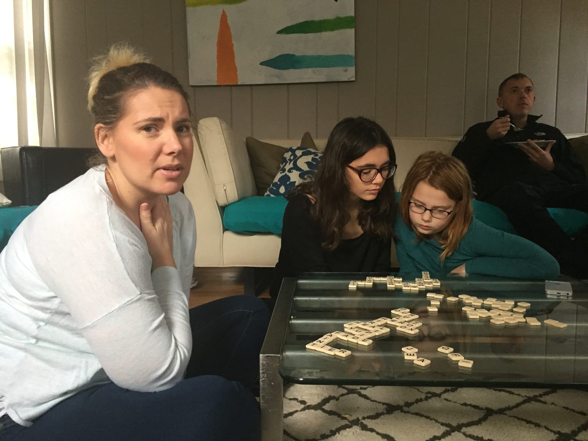 Woman and two girls play Scrabble indoors