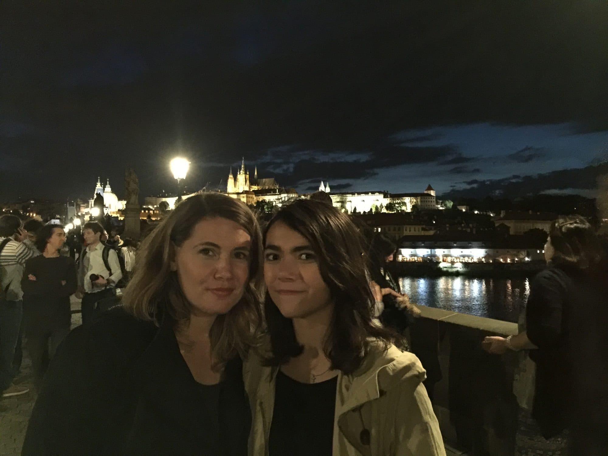 Two women pose at night by a lit-up castle