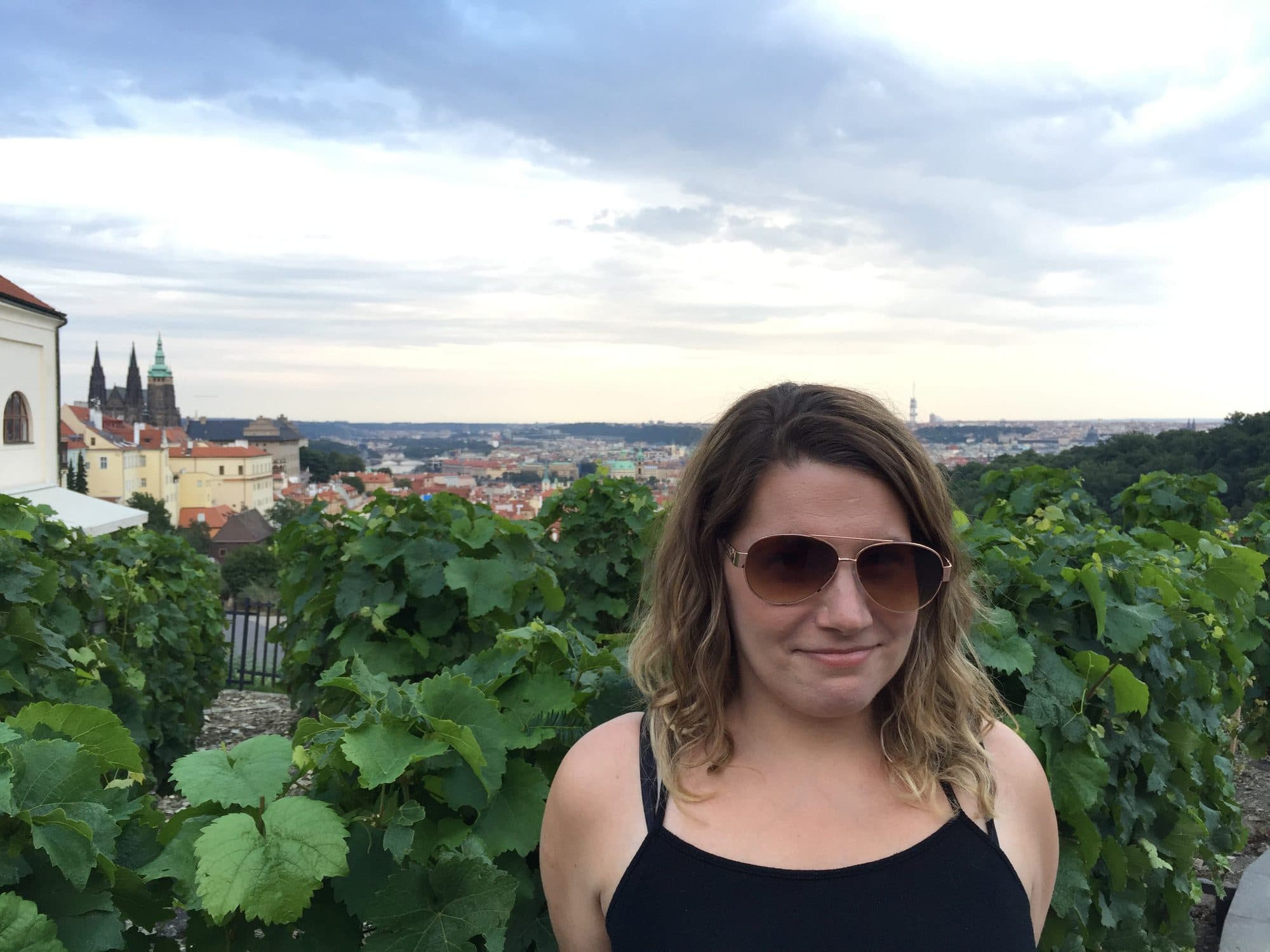 Woman stands in a hillside vineyard at sunset