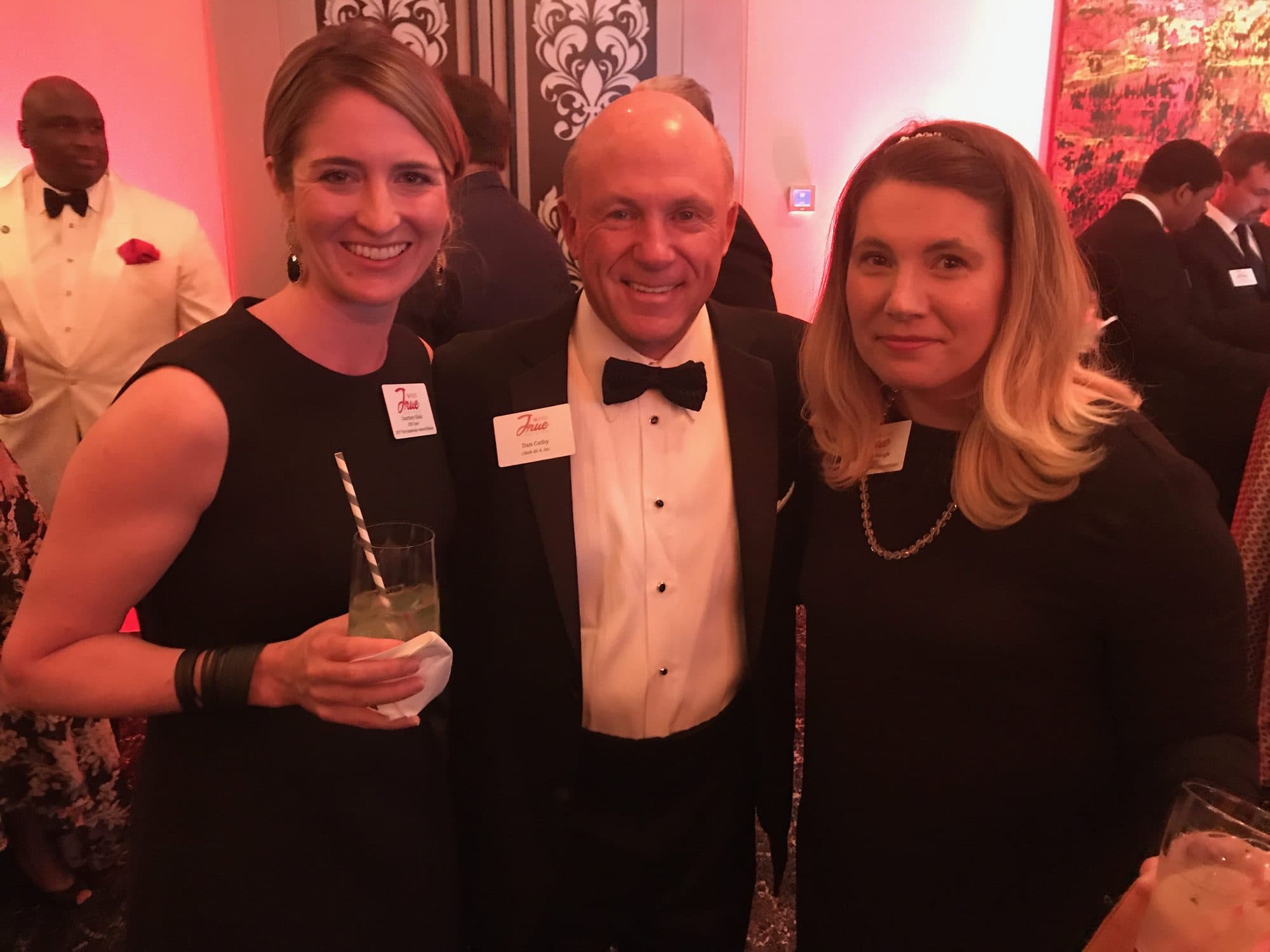 Woman poses with two men at a formal gala