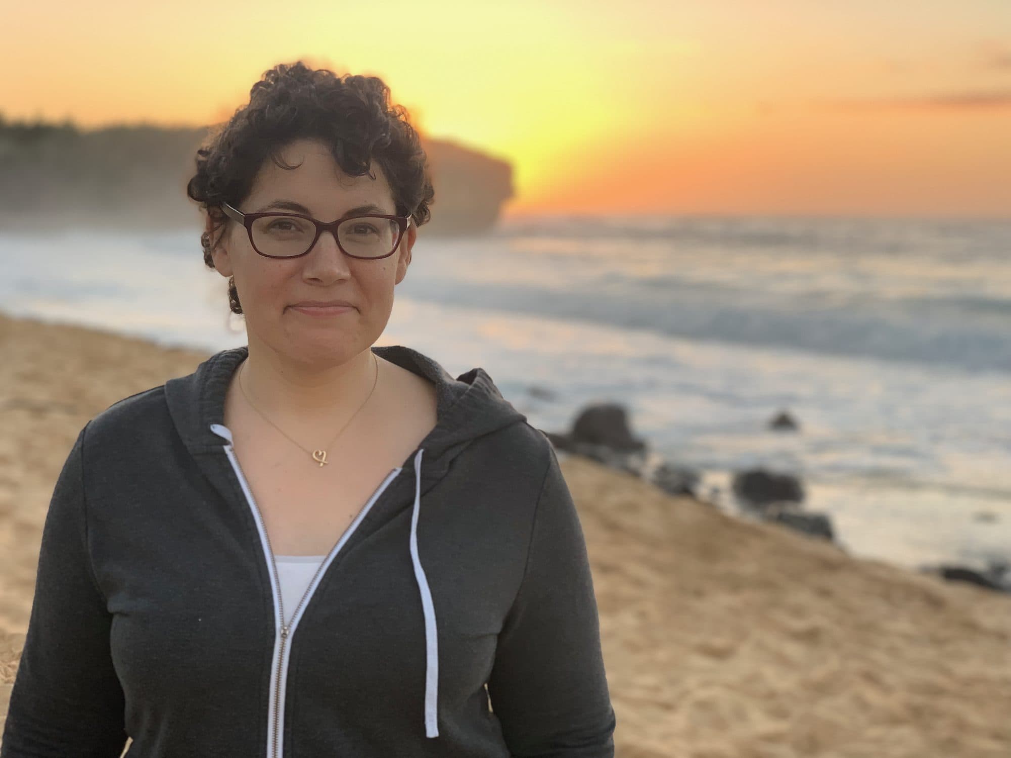 Woman stands on a beach at sunset