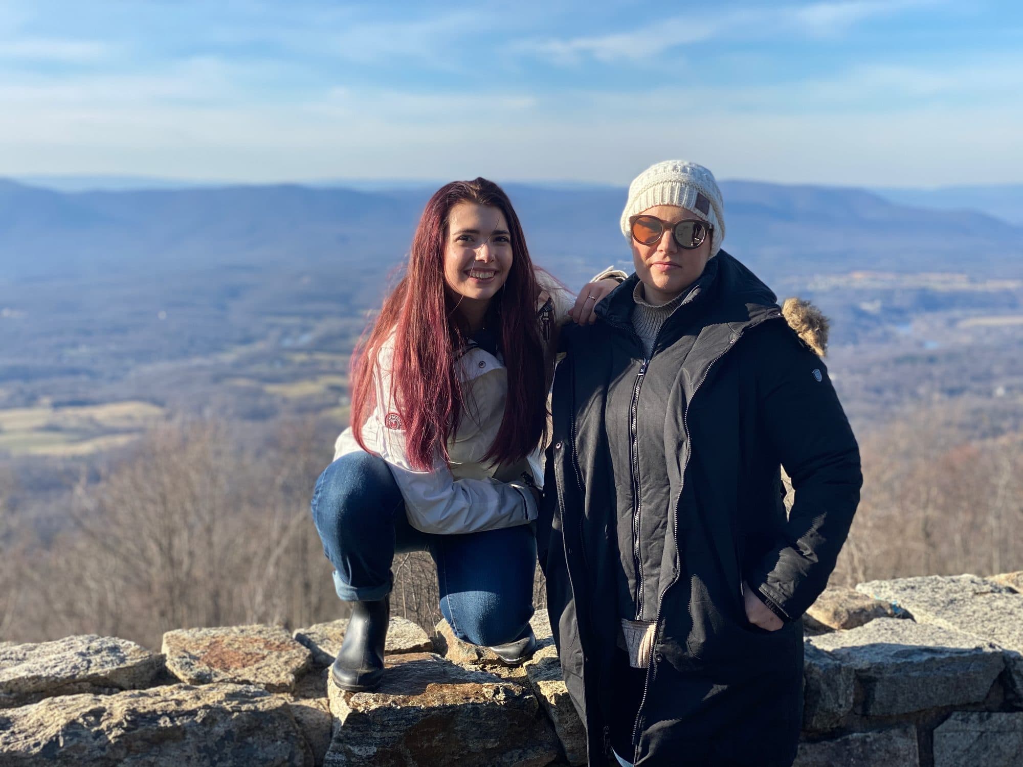 Two women pose on a mountain overlook