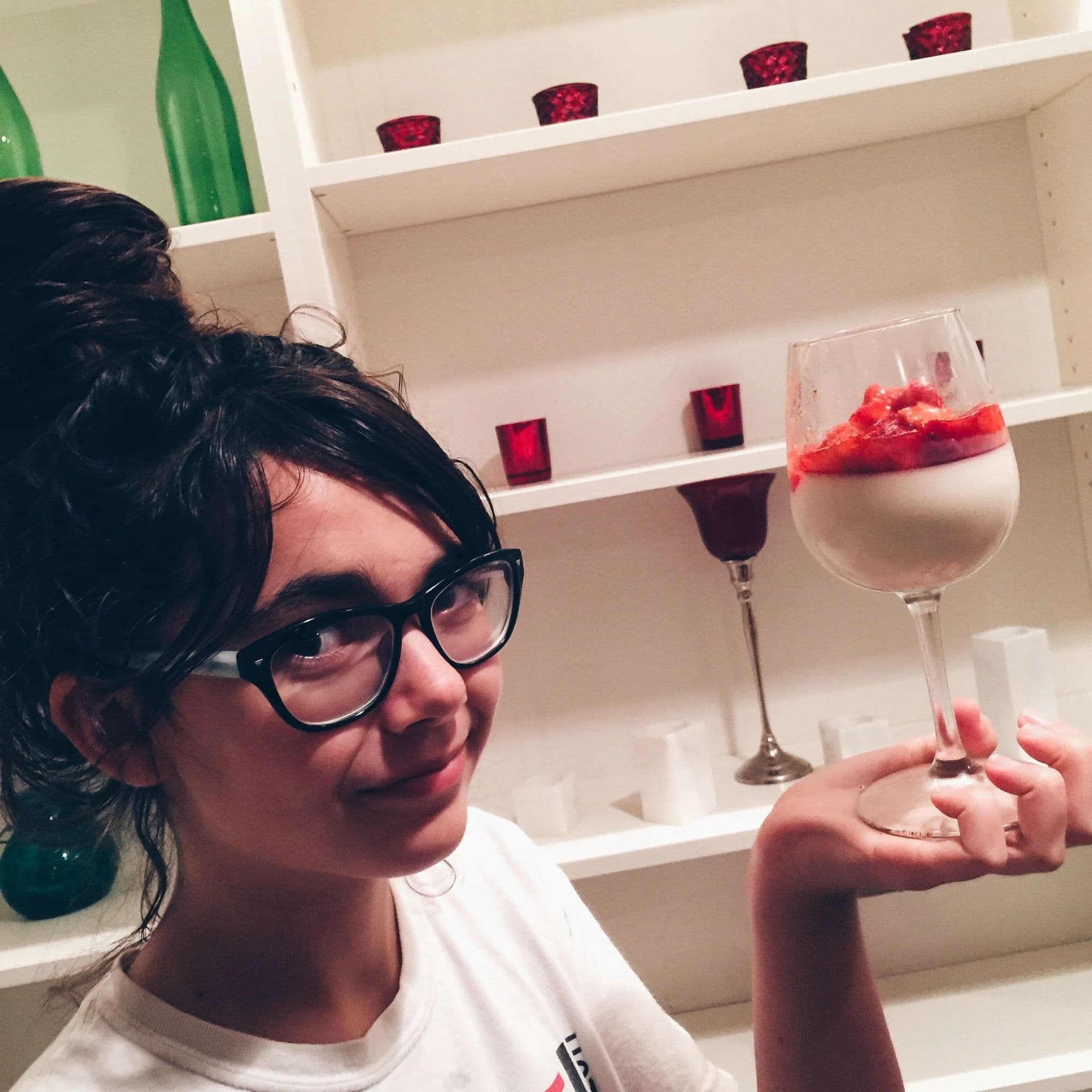 A girl in glasses holding up a glass of strawberry punch at the Valentine's table