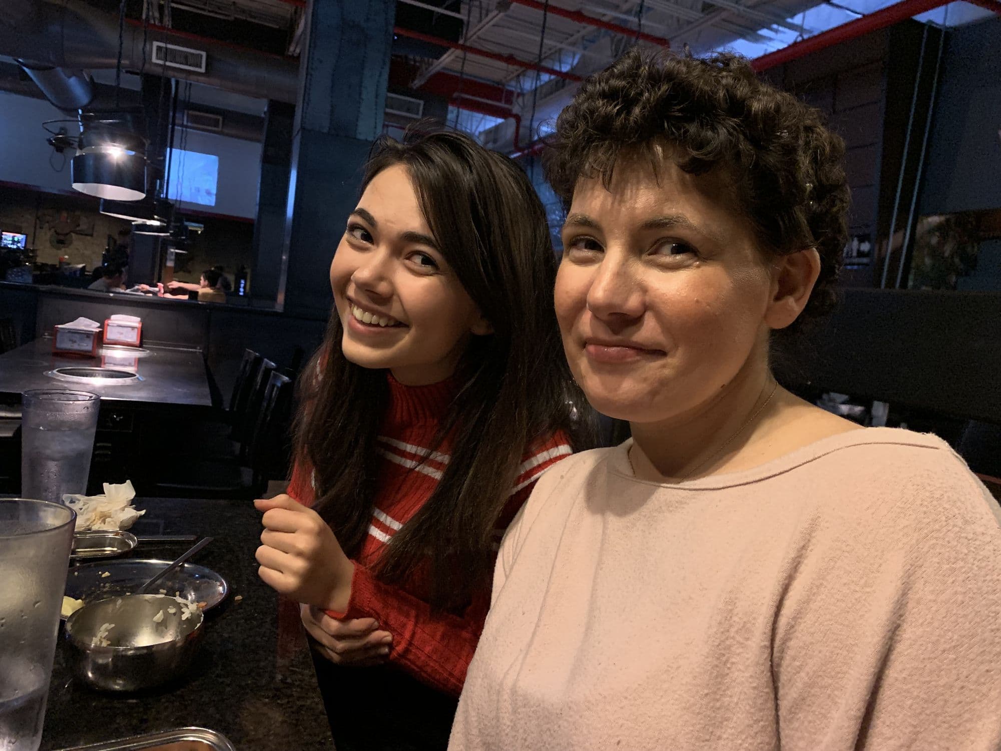 Two women posing at a restaurant bar