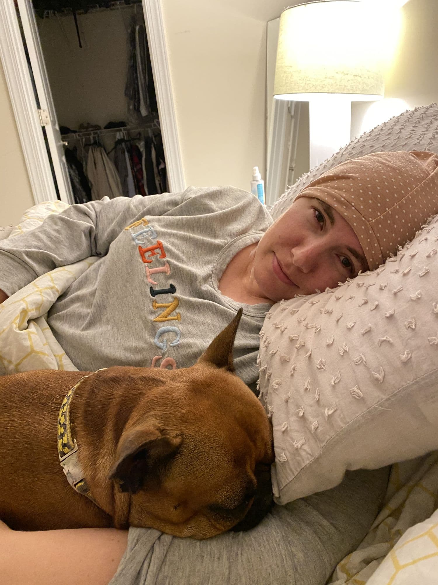Woman in a headscarf holding a small dog indoors