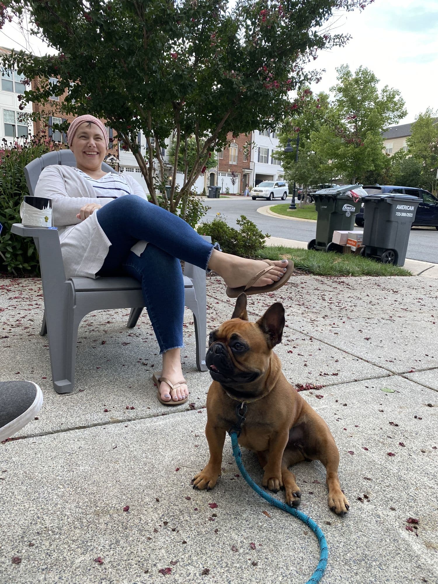 Woman seated outdoors with a small dog on a leash