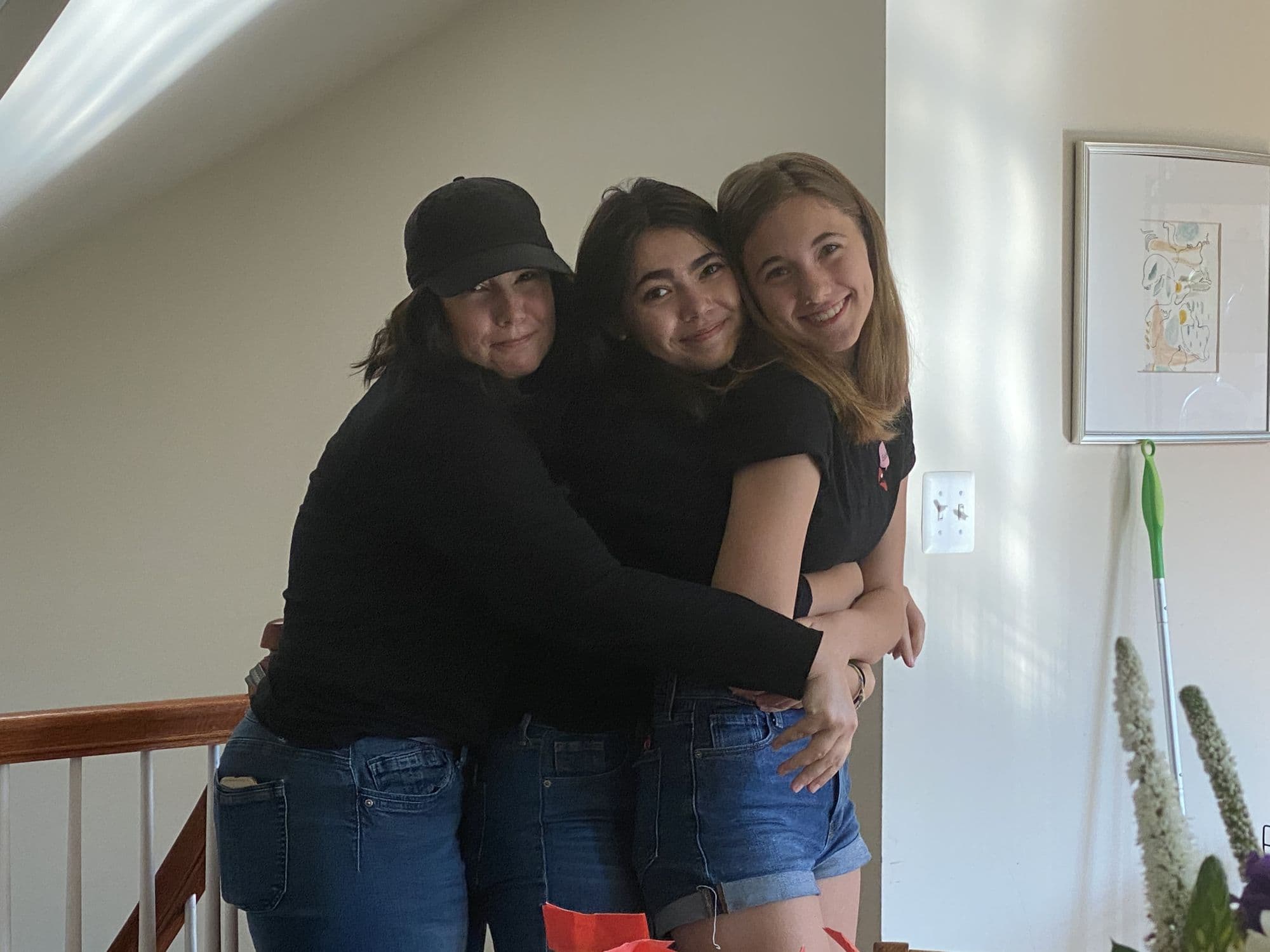 Three people embracing indoors dressed in black