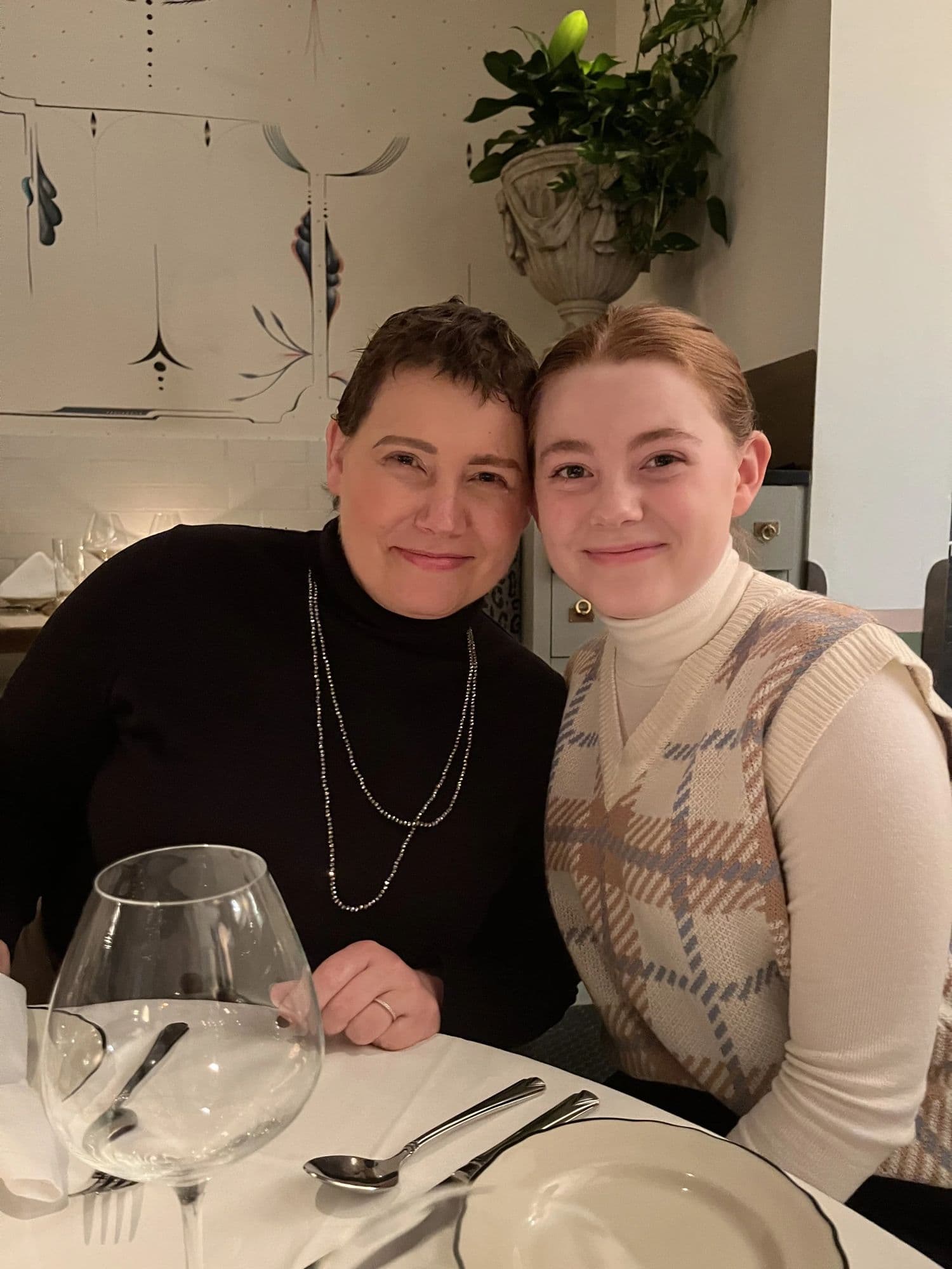 Gretchen and one of her daughters at a restaurant table set with wine glasses