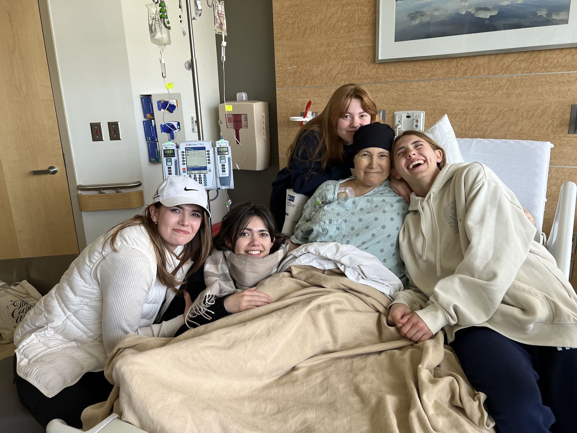 Four people gathered on a hospital bed