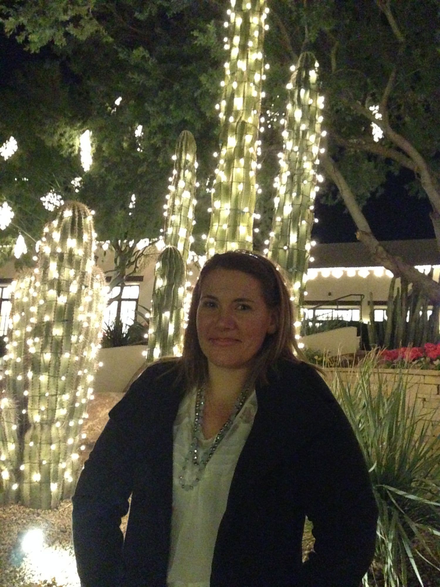 Woman smiling under string-lit trees at night