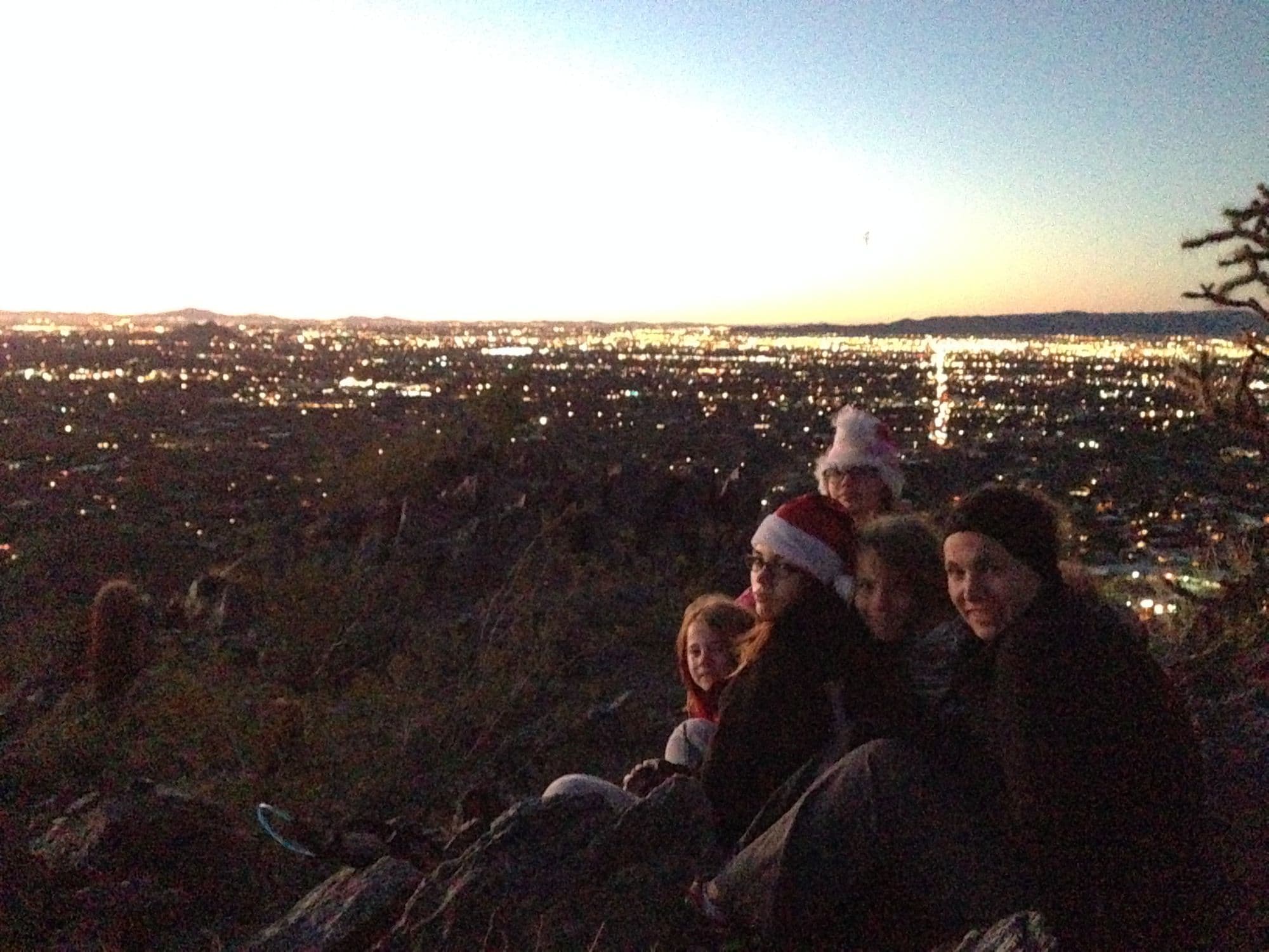 Group on a hillside at dusk in santa hats